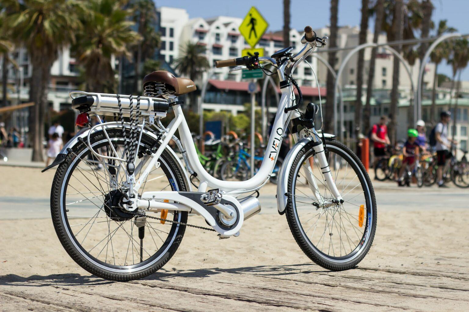 a white bicycle parked on a sandy beach