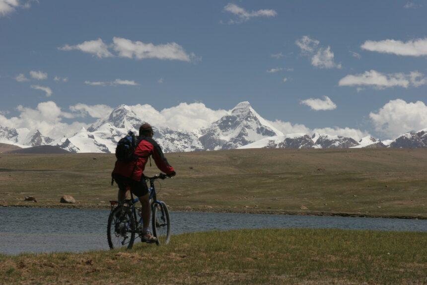 man in black jacket riding bicycle on brown field during daytime