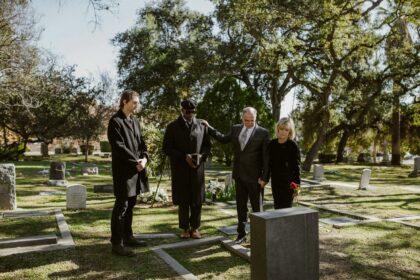 People Weraing Black and Standing Over a Grave