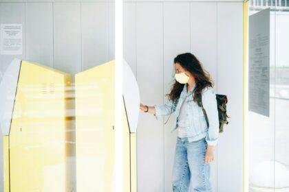 Young woman withdrawing money in face mask at ATM