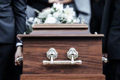 Coffin, people and funeral with death, grief and service with family carry casket to grave outdoor.