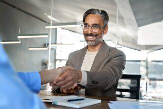 Happy mature business man manager and recruit handshake at job interview.