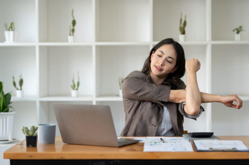 A young Asian businesswoman sits in a chair relieved from fatigue as she sits in the office with a h