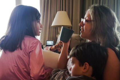 Family fun in home sweet home with generation z kids being kids to millennial mom on a couch.