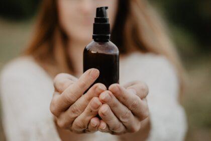 Female hands holding a dark unmarked bottle, cosmetics, natural remedies.